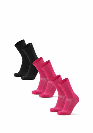 Drie paar zwarte sokken en drie paar roze sokken diagonaal gerangschikt op een witte achtergrond.