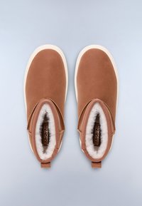 Zapatos marrones sin cordones con un upper de cuero suave, suela de goma blanca y forro suave y esponjoso visible en la apertura. Sin marcas visibles.