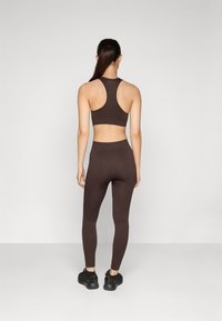 Haut de sport marron à côtes avec un design dos nageur, assorti de leggings taille haute, le tout en tissu extensible et ajusté.