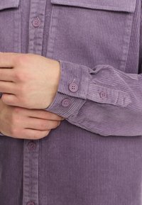 Paars corduroy shirt met verticale ribbels, met knoopmanchetten en een borstzak. Inclusief bijpassende ronde knopen voor sluiting.