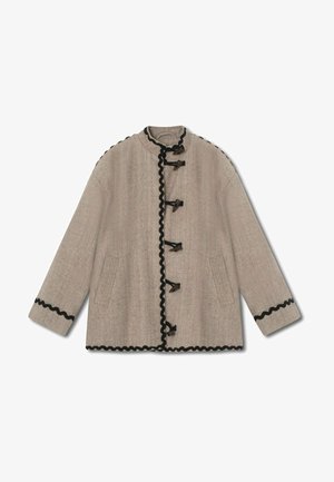 Beige jacket in herringbone pattern, featuring a stand-up collar, black scalloped trim, toggle fastenings, and two side pockets.