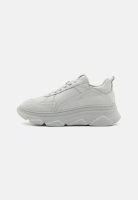 Witte leren sneaker met suède accenten, dikke rubberen zool, gestructureerde panelen, vetersluiting aan de voorkant en logo-detail op de zijkant.
