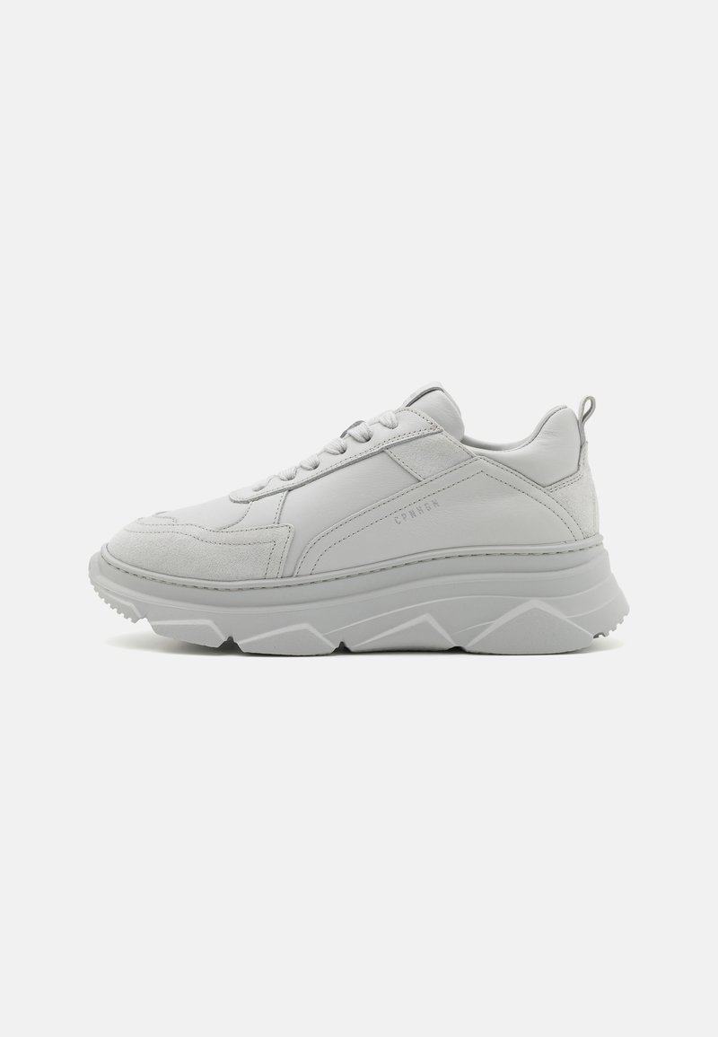 Witte leren sneaker met suède accenten, dikke rubberen zool, gestructureerde panelen, vetersluiting aan de voorkant en logo-detail op de zijkant.