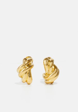 Boucles d'oreilles en métal doré avec un design torsadé, présentant des surfaces lisses et des bords arrondis, mettant en valeur une finition réfléchissante et brillante.