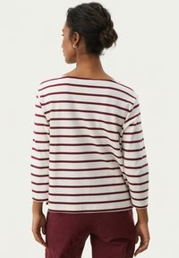 Maglietta a maniche lunghe a righe bianche con linee color bordeaux, caratterizzata da un collo a barca e una vestibilità rilassata, realizzata in morbido cotone.