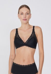 Czarna koronkowa braletka z dekoltem w kształcie litery V, z regulowanymi ramiączkami i falbaniastymi brzegami, w komplecie z pasującymi majtkami o wysokim stanie.