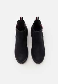 Mustat mokkanahkaiset nilkkurit, joissa on sileä pinta, sivuvetoketju ja raidallinen vetokahva takana. Pyöreä kärki ja pehmustettu sisus.