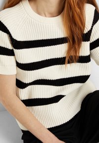 Strikket sweater med sort og hvid vandret striber, korte ærmer, en ribbet struktur og rund halsudskæring. Casual fit.