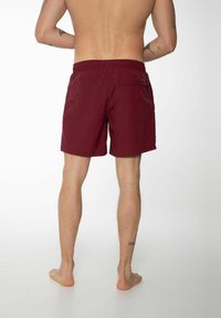 Shorts de bain bordeaux avec une taille élastique, une poche arrière unique et un tissu léger et lisse. Coupe ajustée avec coupe droite.