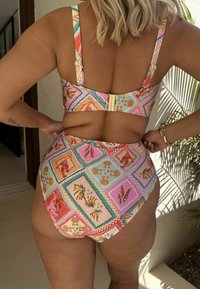 Aukštos liemens bikini, margas su geometriniu raštu, kuriame pavaizduoti kriauklės ir tropiniai motyvai. Reguliuojamos petnešėlės ir auksinė sagtis nugaroje.