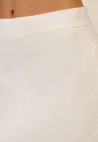 Weißer elastischer Bund mit glattem, weichem Stoffgefühl, der ein nahtloses und minimalistisches Design schafft. Keine sichtbaren Muster oder Beschläge.