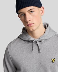 Gray hoodie with a drawstring, featuring a small yellow embroidered logo on the left chest. The model wears a navy ribbed beanie.
