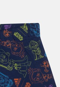 Shorts in cotone blu navy con grafiche colorate dei personaggi di Star Wars in arancione, verde e blu. Include il marchio Adidas sulla cintura.