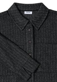 Camisa de patrón de pata de gallo en negro y gris, diseño abotonado, con cuello y un bolsillo en el pecho, con botones oscuros y tela texturizada.