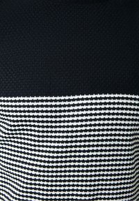 Strickpullover mit einem oberen Abschnitt in solidem Schwarz und einem unteren Abschnitt mit horizontalen schwarz-weißen Streifen. Strukturierter Stoff.