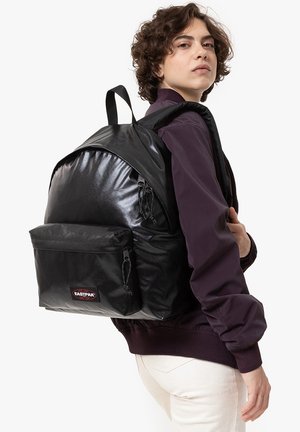 Le sac à dos Eastpak noir présente une finition brillante, un grand compartiment principal, une poche zippée à l'avant, des bretelles ajustables et une forme arrondie.