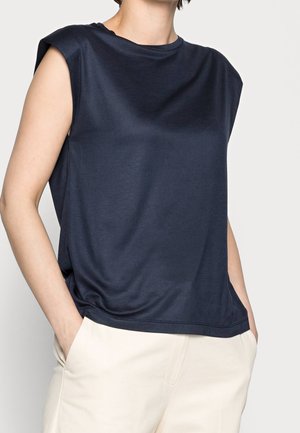 Top sin mangas de color azul marino oscuro con escote redondo y ajuste relajado, hecho de tela suave. Combinado con pantalones de color claro.