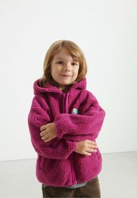 Fleece hoodie i lys pink, med frontlynlås og lommer, i en hyggelig tekstur og med et lille farverigt logo på brystet.