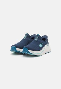 Pantofi sport Skechers cu un superior din plasă albastru marine respirabil, accente albastre deschise, design slip-on și o talpă din spumă albă ușor amortizată.