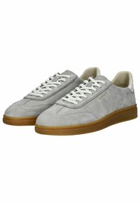 Zapatillas de ante gris con cordones blancos y parte superior lisa. Presentan una suela de goma y un detalle del logo en dorado en el lateral.