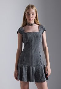 Robe rayée grise avec des manches courtes, un décolleté carré, un corsage ajusté et un ourlet évasé. Dotée d'un tissu lisse et d'une texture subtile.