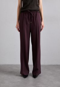 Bordeaux wijdvallende broek van zacht materiaal met een elastische tailleband en verstelbaar trekkoord, voorzien van goudkleurige hardware accenten.