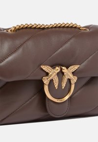 Borsa a tracolla in pelle marrone con una finitura trapuntata, manico a catena dorata e un dettaglio di chiusura a forma di uccello in ottone dorato.