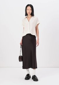 White striped short-sleeve button-up shirt, black satin midi skirt, black platform shoes, white crew socks, and a small handbag.