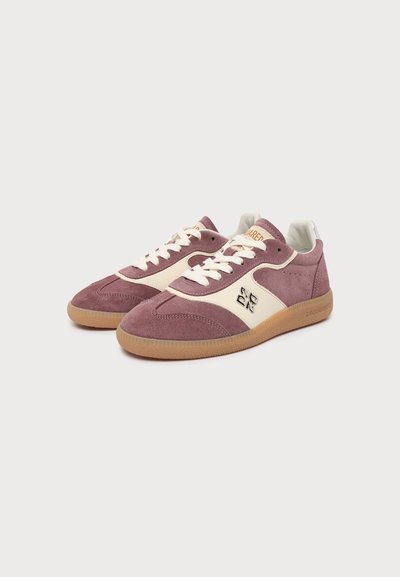 Paire de baskets en daim mauve et crème avec des lacets blancs, détail du logo sur le côté et semelles en caoutchouc beige, présentées sur fond blanc.