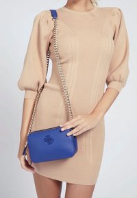 Borsa a tracolla blu in pelle con tracolla a catena e logo impresso, forma rettangolare, design elegante e texture liscia.