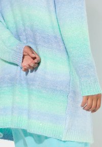 Kevyt neulepaita sinivihreissä sävyissä. Ominaisuuksia pitkät hihat, ribbireunat ja löysä malli. Pintakuviointi kimalteilla.