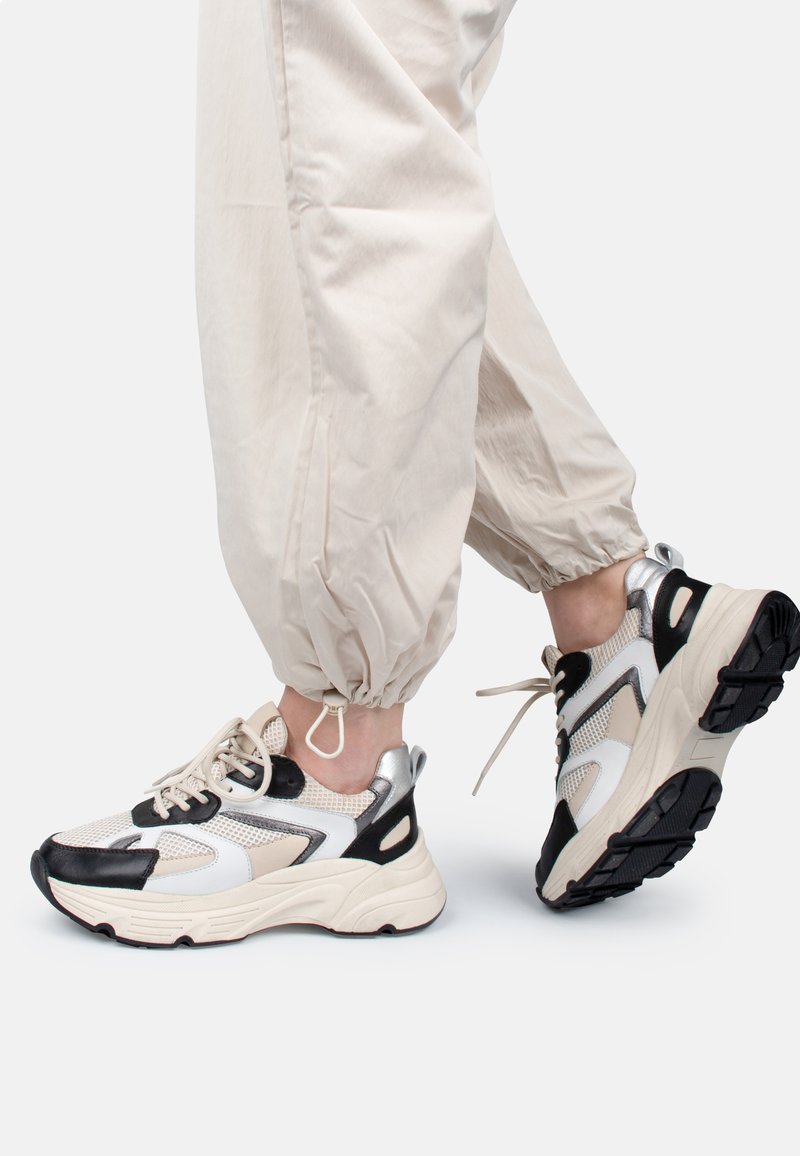 Chunky Sneaker in Creme, Schwarz und metallisch silbernem Mesh. Verfügt über eine strukturierte Sohle, ein schnürbares Design und gepolsterte Knöchelunterstützung.