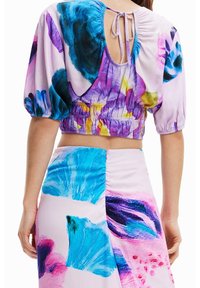 Vícebarevný květinový crop top s nabíranými rukávy a zavázaným zadním dílem, spárovaný s odpovídající sukní zdobenou výraznými modrými a růžovými akvarelovými vzory.