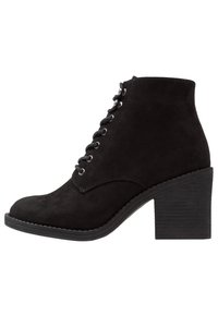 Bottine en daim noire avec lacets à l'avant et talon bloc, vue latérale sur fond blanc.