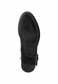 Suela de zapato negra con un patrón texturizado y acanalado, con un acabado de goma suave que incluye un pequeño logotipo y un detalle de acento metálico.