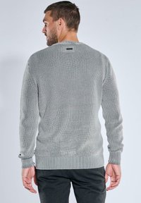 Grauer gerippter Pullover mit langen Ärmeln, Rundhalsausschnitt und strukturiertem Finish; mit einem eng anliegenden Bund und Bündchen für eine figurbetonte Passform.
