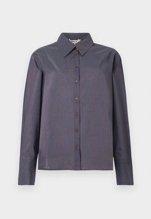 Tīra piedurknēm, ar pogām, jaka tumši zila ar plānām brūnām vertikālām svītrām. Ir klasiskā apkakle un gluda, nedaudz teksturēta auduma.