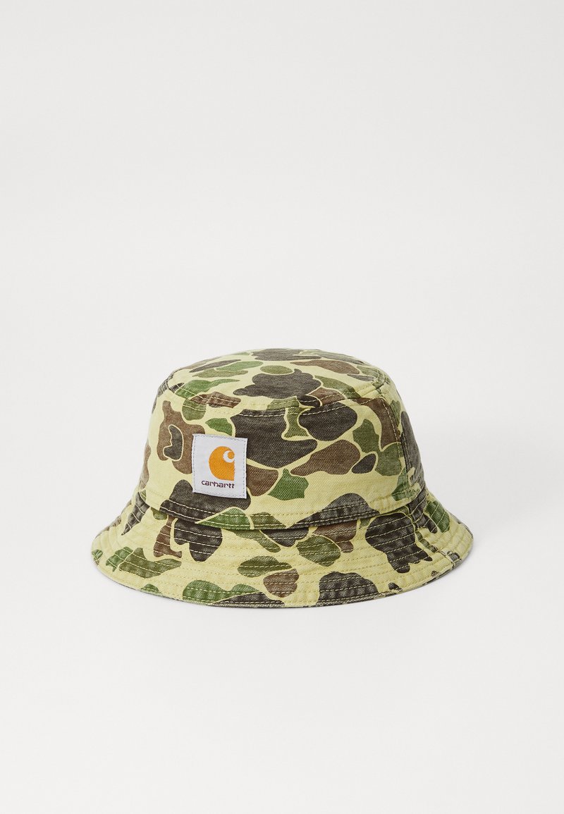 Camo bucket hat in shades of green and brown fabric, features a white label with an orange logo. Soft, flexible brim and textured surface.