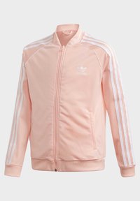 Vaaleanpunainen vetoketjullinen takki, jossa valkoiset raidat hihoissa, resorit hihansuuissa ja sileä, synteettinen kangas. Rintakehällä logo.