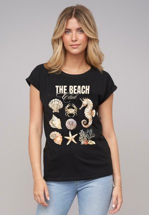 Černé tričko s krátkým rukávem s potiskem mušlí, mořských koníků, kraba a korálu, spolu s textem "THE BEACH Club" v krémové barvě.