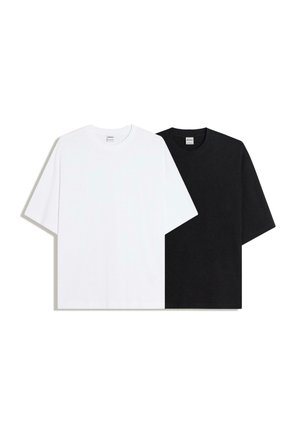 Dve jednoduché tričká s krátkym rukávom, jedno biele a jedno čierne, položené na rovnej ploche a prekryté na bielom pozadí.