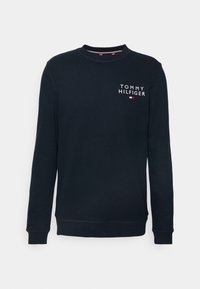 Sweat-shirt col rond bleu marine avec des manches longues et le logo "Tommy Hilfiger" ainsi qu'un emblème de drapeau sur la poitrine supérieure gauche.