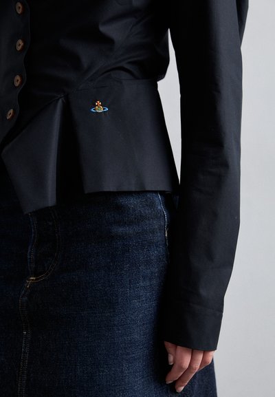 Μαύρο πουκάμισο με κουμπιά και σχέδιο peplum, με μια μικρή πολυχρωμία κεντημένη λεπτομέρεια στη μέση, συνδυασμένο με σκούρο τζιν.