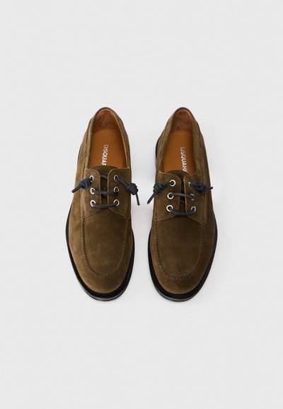 Chaussures en daim marron avec une finition lustrée, dotées de lacets et d'œillets noirs, d'un bout arrondi et d'une semelle en caoutchouc noire contrastante.