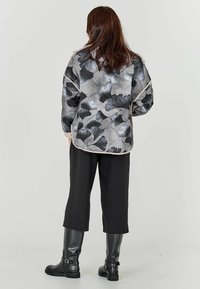 Zwart en grijs bloemenpatroon jasje met een casual pasvorm, gecombineerd met zwarte cropped broek en kniehoge zwarte leren laarzen.