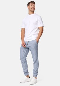 Weißes Baumwoll-T-Shirt kombiniert mit hellblauen Jogginghosen, die einen Kordelzug und elastische Bündchen haben, ergänzt durch weiße Sneakers.