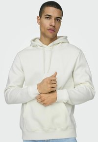 Helle beige Kapuzenjacke aus weichem Stoff mit einer Fronttasche, Kordelzug-Kapuze und gerippten Bündchen. Slim Fit mit glatter Textur.