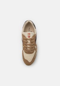 Braun- und cremefarbene Sneaker mit strukturierter Wildleder-Oberfläche, einem pinken Akzent und passenden Schnürsenkeln, glatter Gummisohle und Logo auf der Zunge.