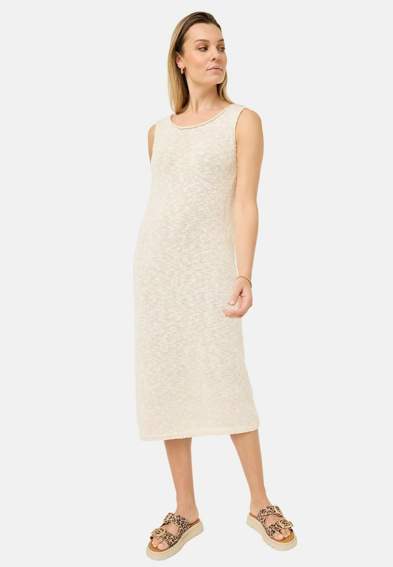 Strickkleid in Cremefarbe mit Rundhalsausschnitt, taillierter Form und strukturiertem Finish. Kombiniert mit Sandalen im Leopardenmuster.