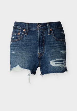 Shorts di denim blu con strappi consumati, orlo sfrangiato, tasche frontali, passanti per cintura e chiusura con bottone su uno sfondo semplice.